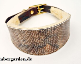 May include: A brown leather dog collar with a white faux fur lining and a gold metal buckle. The collar has a snakeskin pattern.