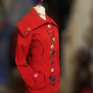 May include: Red coat with a large collar and a row of colorful buttons and embroidered flowers down the front.