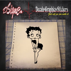 May include: Black and white cartoon illustration of a woman with a short black bob hairstyle, wearing a black dress and high heels. The illustration is on a white background.