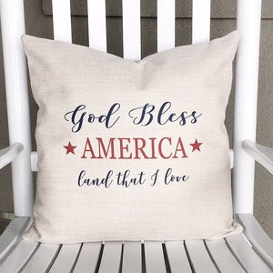 May include: A white rocking chair with a pillow that says "God Bless America* land that I love" in red, white, and blue.