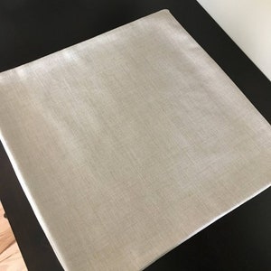 May include: A plain, light beige throw pillow cover made of a textured fabric.
