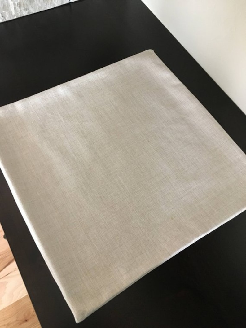 May include: A plain, light beige throw pillow cover made of a textured fabric.