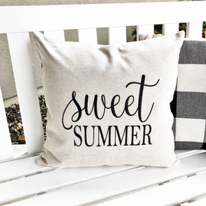 May include: A white throw pillow with the text "sweet summer" in black cursive lettering.