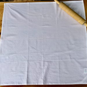 Peut inclure: Une serviette de cuisine en coton blanc avec un rouleau &agrave; p&acirc;tisserie en bois sur le dessus.