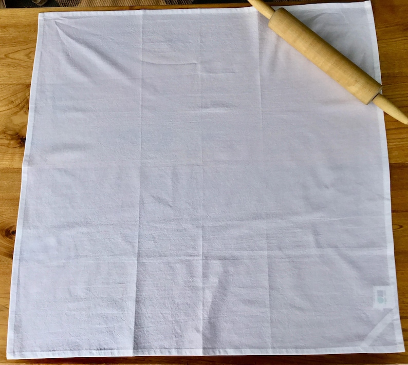Peut inclure: Une serviette de cuisine en coton blanc avec un rouleau &agrave; p&acirc;tisserie en bois sur le dessus.