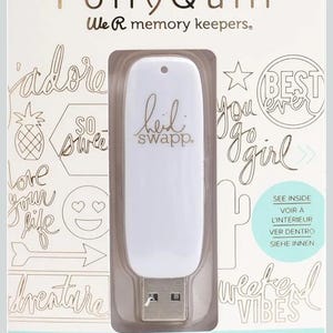 Pode incluir: Uma unidade USB branca com o texto "heid swapp" é exibida em uma embalagem de plástico transparente. A embalagem também apresenta as palavras "Foil Quill" e elementos de texto decorativos.