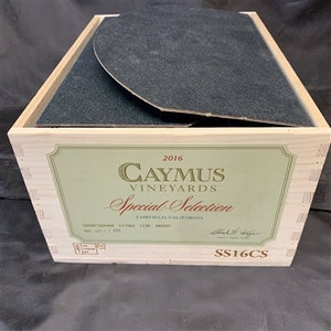 May include: A wooden wine box with a black felt liner. The label reads "2016 Caymus Vineyards Special Selection, Fiddletown, California, SS16CS".