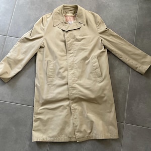 Op de afbeelding: Een beige trenchcoat met knoopsluiting en twee zakken. De jas heeft een klassiek ontwerp en is gemaakt van een lichtgewicht stof.