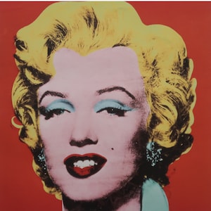 May include: A pop art portrait of Marilyn Monroe with bright yellow hair, blue eyeshadow, and red lips against a red background.