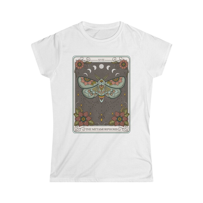 May include: White t-shirt with a graphic of a tarot card featuring a moth with floral accents and the text "XVII THE METAMORPHOSIS".