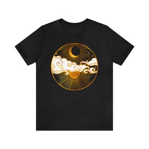 K&ouml;nnte beinhalten: Schwarzes T-Shirt mit einem goldenen kreisf&ouml;rmigen Design, das einen Halbmond, die Sonne und Wolken zeigt.