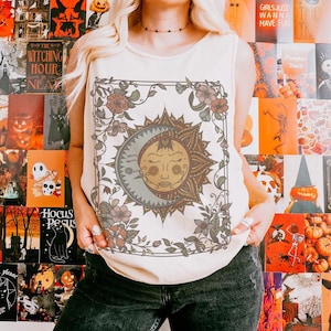 Op de afbeelding: Cr&egrave;mekleurige tanktop met een zon- en maanontwerp met bloemaccenten. De afbeelding is omlijst door een bloemenrand. De achtergrond is een collage van Halloween-posters.