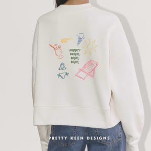 May include: White sweatshirt with colorful beach-themed graphics, including a sun, ice cream cone, and beach chair. The text "Jennie's Beach Bash" is also featured. The bottom of the sweatshirt has the text "Pretty Keen Designs".