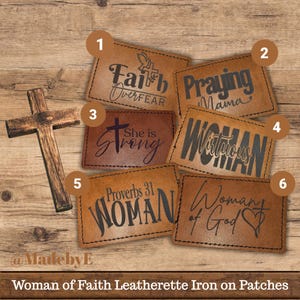 May include: A collection of brown leatherette iron-on patches with black text. The patches feature phrases like "Faith Over Fear," "Praying Mama," "She is Strong," and "Woman of God." A wooden cross is also present.