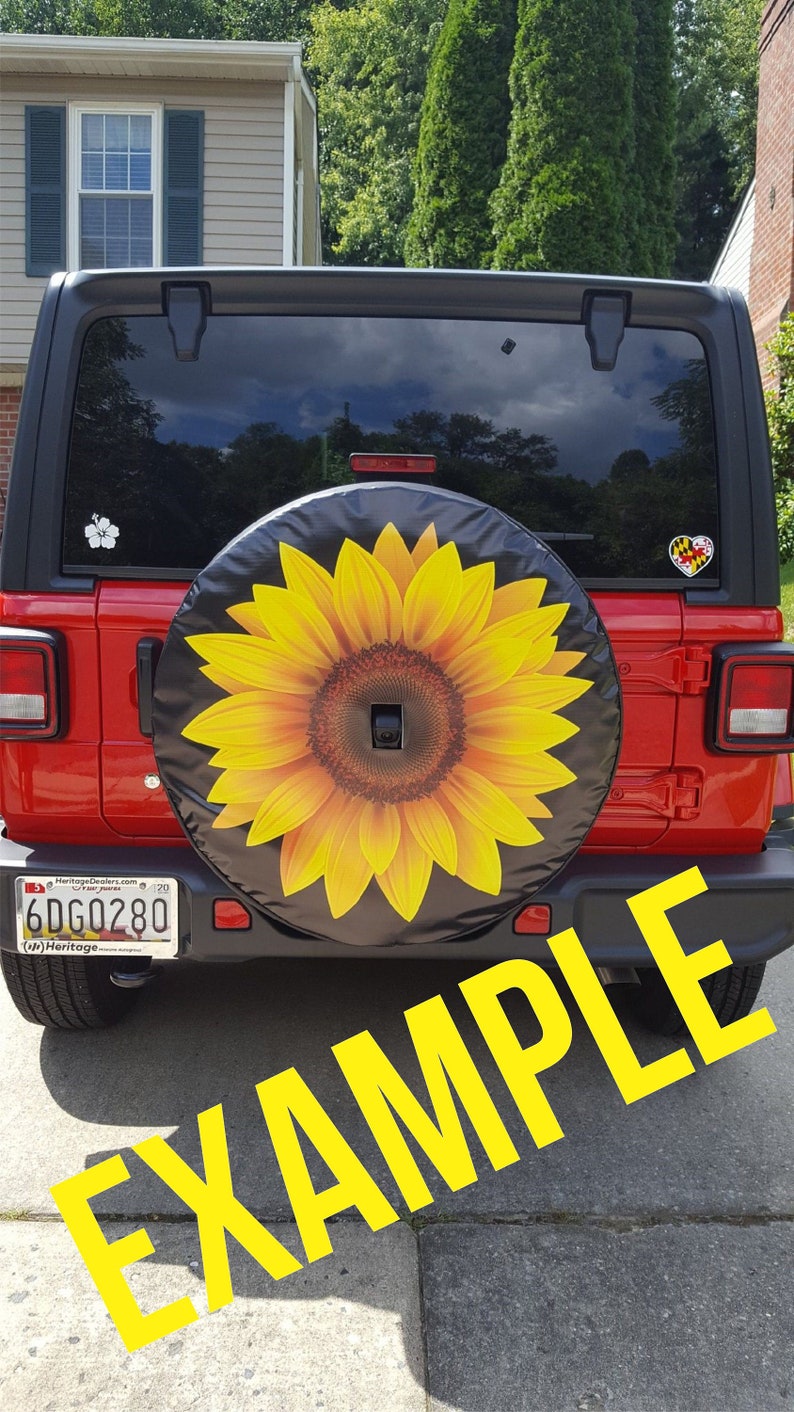 May include: A red Jeep Wrangler with a black spare tire cover featuring a yellow sunflower design. The license plate reads "6DG0280".