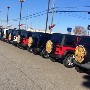 May include: A row of black and red Jeep Wranglers with custom gold and black spare tire covers. The spare tire covers have the Jeep logo and the words "Atlanta Jeep" and "Jeepmark.com".