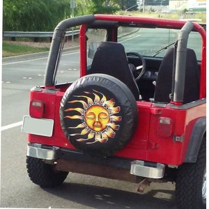 May include: A red Jeep with a black spare tire cover featuring a yellow sun with a closed-eye face and yellow rays.