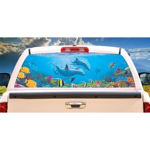 May include: A white pickup truck with a rear window decal featuring a colorful underwater scene with two dolphins swimming through coral reefs and tropical fish.