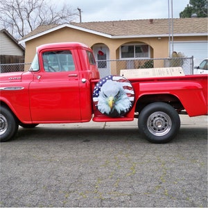 May include: A red Chevrolet truck with a spare tire cover featuring an American flag with a bald eagle design.