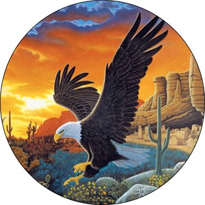 May include: A bald eagle with outstretched wings soars over a desert landscape at sunset. The eagle is in flight, with its talons extended. The background features a rocky canyon, cacti, and a distant village.