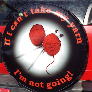 May include: Black spare tire cover with the text "If I can't take my yarn I'm not going!" in white and red lettering. The cover features two red balls of yarn and knitting needles.