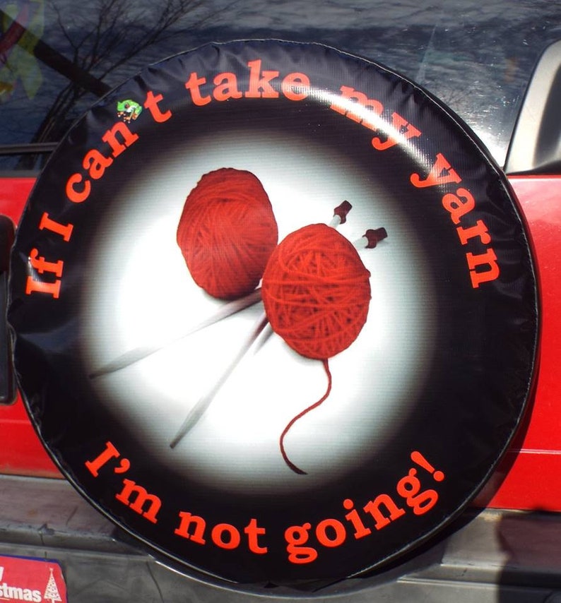 May include: Black spare tire cover with the text "If I can't take my yarn I'm not going!" in white and red lettering. The cover features two red balls of yarn and knitting needles.