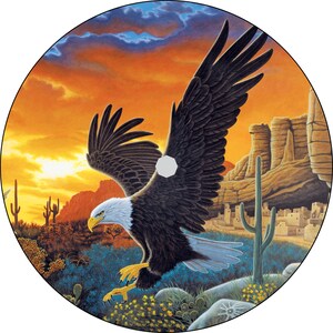 May include: A bald eagle with outstretched wings soars over a desert landscape at sunset. The eagle is in flight, with its talons extended. The background features a rocky cliff face, cacti, and a distant village.