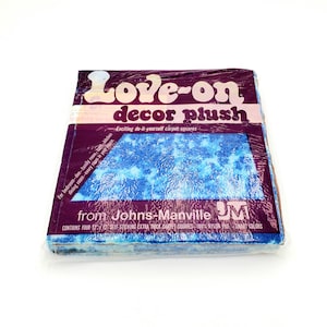 May include: A package of "Love-on decor plush" carpet squares. The packaging is a deep purple with white and pink text. The carpet squares are blue with a white pattern. The package reads "Exciting do-it-yourself carpet squares."