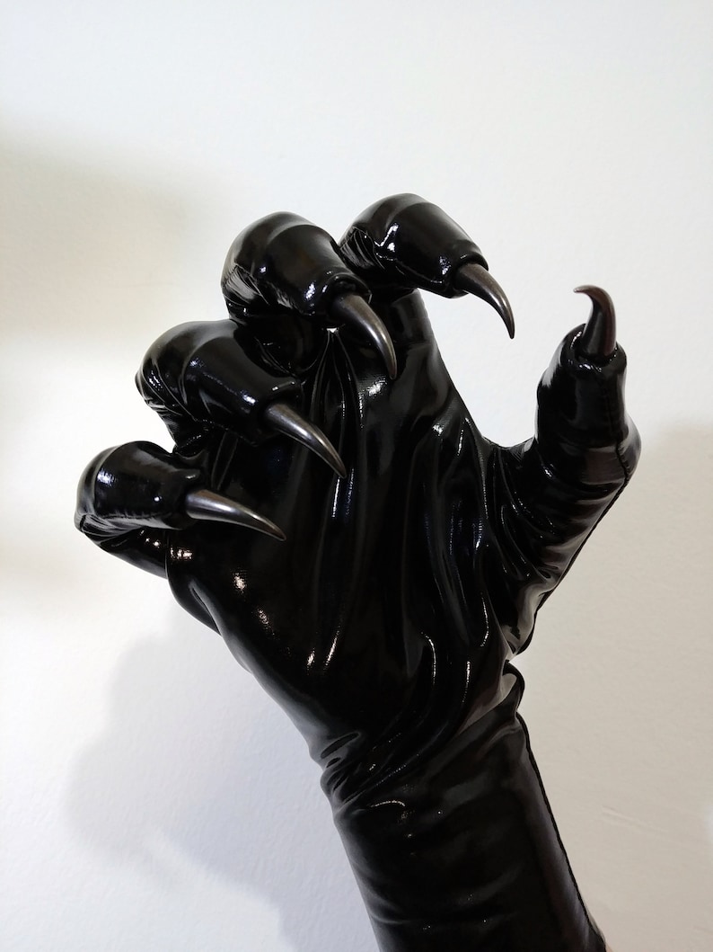 May include: Black leather gloves with long claws. The gloves are shiny and have a textured surface.