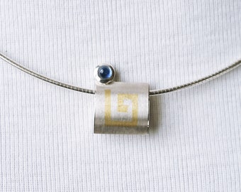 Pendant with gold insert and sapphire.