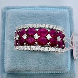 May include: A white gold ring with a band of round diamonds and a row of oval rubies.