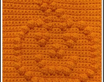 May include: Close-up of a crocheted fabric with a textured pattern. The fabric is a bright orange color and has a repeating pattern of small bumps.