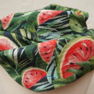 Könnte beinhalten: Ein grüner Stoff-Halswärmer mit Wassermelonen-Druck. Der Stoff hat eine strukturierte Optik und Haptik.