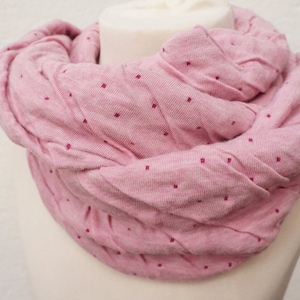 Könnte beinhalten: Ein rosafarbener gestrickter Infinity-Schal mit kleinen weißen Punkten.