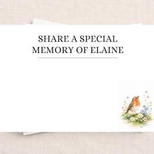 May include: A white card with the text "SHARE A SPECIAL MEMORY OF ELAINE". A watercolour illustration of a robin bird on flowers is in the lower right corner. The card is on a light beige surface.