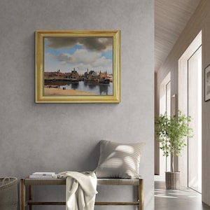 a modern interior design with a large painting of a cityscape hanging on a gray wall above a wooden bench. The painting is framed in gold and is the focal point of the room. The bench is positioned in front of a window, allowing natural light to illuminate the space. A potted plant is also present in the room, adding a touch of greenery to the overall design.