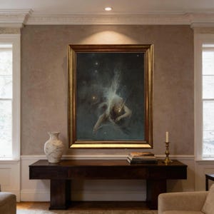 May include: A framed oil painting depicting a celestial figure in a dark, starry expanse, rendered in muted tones of gray, white, and gold. The artwork is encased in a thick, ornate gold frame and hangs centered on a wall above a dark wooden console table.