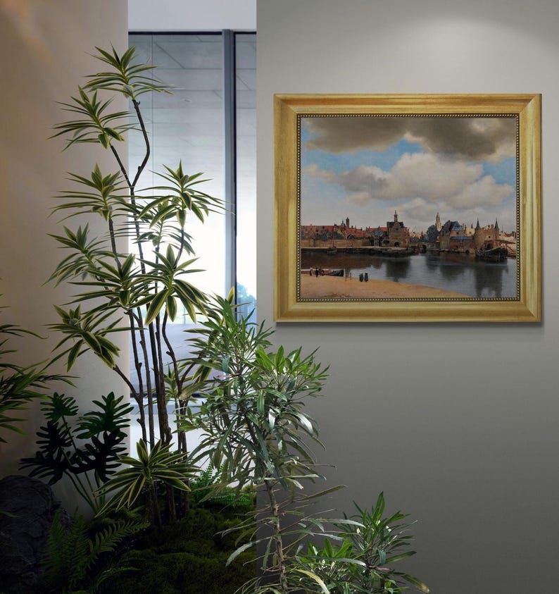 a framed painting of a cityscape with a river in the background, hanging on a wall next to a potted plant.