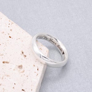 Può includere: Un anello a fascia d'argento con l'iscrizione "Always By Your Side" e un piccolo simbolo di cuore.