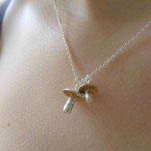 May include: A silver chain necklace with a gold and silver mushroom charm pendant.