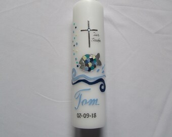 May include: White baptism candle with a silver cross, blue and green fish, and blue waves. The candle is decorated with the text "Zur Taufe" and the name "Tom" with the date "07-09-18".