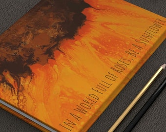 May include: A yellow and brown journal with the text "In a world full of roses, be a sunflower" on the cover.