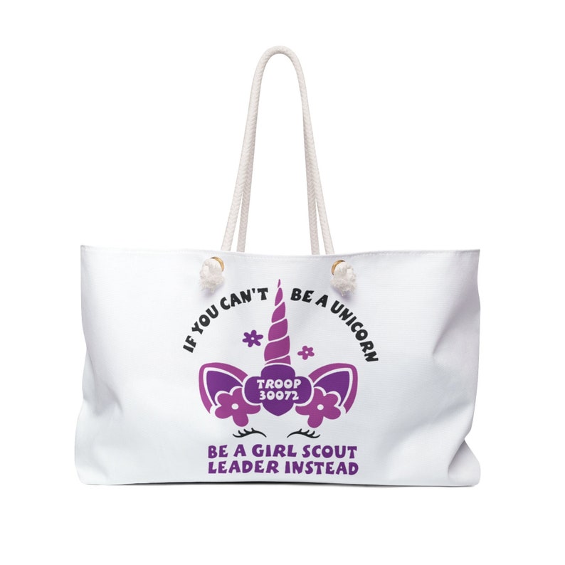 May include: White canvas tote bag with a purple unicorn graphic and the text "If you can't be a unicorn, be a Girl Scout leader instead." The unicorn has a purple horn and flowers around its head. The text "Troop 30072" is inside a heart shape on the unicorn's chest.