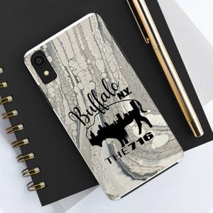 May include: A white phone case with a marbled design. The case has a black silhouette of a buffalo with the text "Buffalo NY The 716" printed on it.