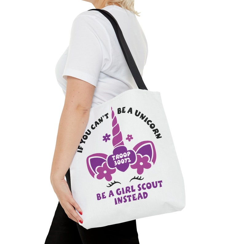 May include: White tote bag with a purple unicorn graphic and the text "If you can't be a unicorn be a Girl Scout instead." The unicorn has a pink horn and flowers. The text "Troop 30072" is inside a heart on the unicorn's forehead.