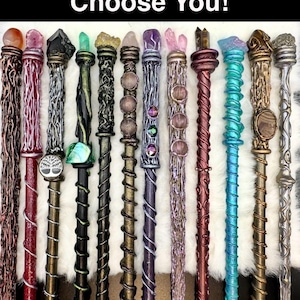 K&ouml;nnte beinhalten: Eine Sammlung handgefertigter Zauberst&auml;be mit verschiedenen Designs und Farben. Jeder Zauberstab hat einzigartige Verzierungen, darunter Kristalle und dekorative Elemente. Der Text "Let The Wand Choose You!" wird oben angezeigt.