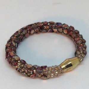 May include: A beaded bracelet with iridescent brown and clear beads. The bracelet has a gold-toned magnetic clasp.