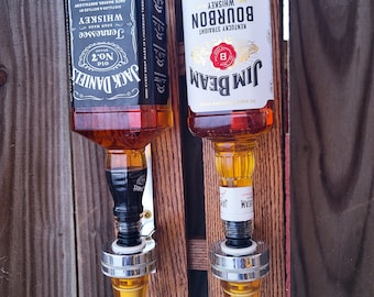 May include: Two liquor bottle dispensers mounted on a wooden wall. The dispensers are filled with Jack Daniel's Tennessee Whiskey and Jim Beam Kentucky Straight Bourbon Whiskey.