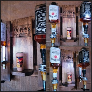 Puede incluir: Un expositor de bar de madera con m&uacute;ltiples dispensadores de botellas de licor. La pantalla presenta el texto "POPPY'S BAR" e incluye botellas de Jack Daniel's y bourbon Jim Beam. Tambi&eacute;n hay un peque&ntilde;o vaso de chupito decorativo.