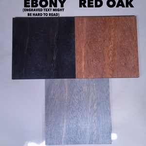 Puede incluir: Tres muestras de madera etiquetadas como "EBONY", "RED OAK" y "GRAY STONE". La muestra de &eacute;bano es negra, el roble rojo es marr&oacute;n y la piedra gris es gris claro. El texto "(ENGRAVED TEXT MIGHT BE HARD TO READ)" est&aacute; encima de la muestra de &eacute;bano.